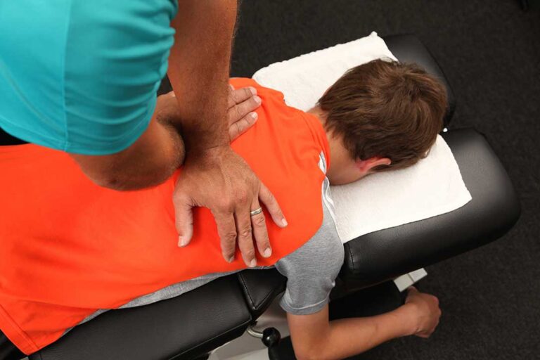 Chiropractor showing a patient a diagram of nerve pathways connecting neck and arm pain