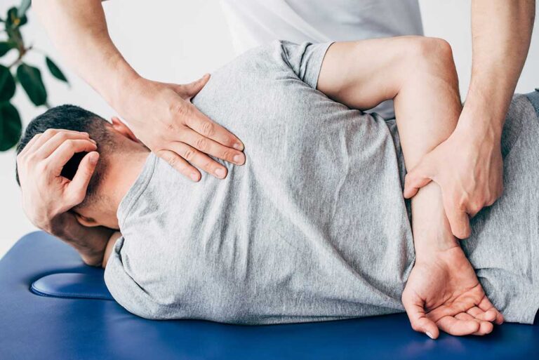 An older adult receiving gentle back care from a health professional in a cozy home setting.